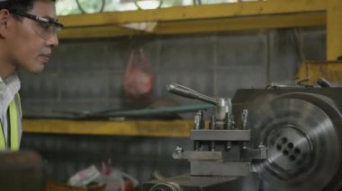 Asyalı profesyonel makine mühendisi ya da üniforma gözlüğü takan operatör güvenlik atölye metal torna fabrikası, ağır sanayi torna işçisi