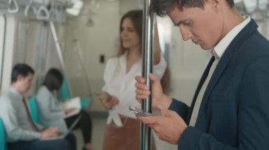 Elektrikli trende internet haberlerini kontrol etmek için modern akıllı telefonu kullanan işadamını kapatıyoruz. Yolcu genç adam, tren yoluyla cep telefonuyla mesaja gidip geliyor.