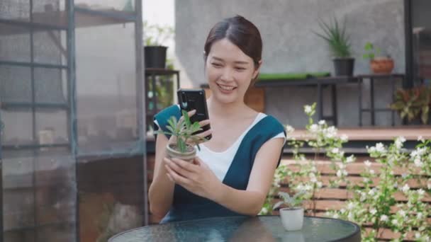 Asyalı Güzel Genç Bir Kadın Akıllı Telefonuyla Sera Yakınlarındaki Bahçede — Stok video