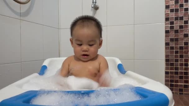幸せなアジアの赤ちゃん小さな男の子は泡泡で遊んでお風呂に入るお湯を流し 小さな子供は家のバスルームの内部に石鹸のついたシャワーを浴び 健康管理と衛生 — ストック動画