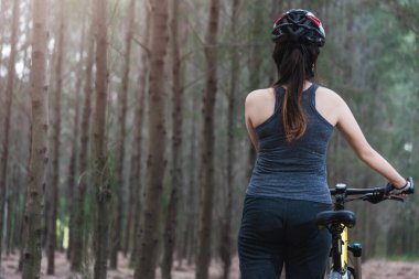 Genç bayan kaskı, yazın ormanda fotokopi çekilen bisiklete biniyor.