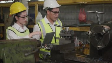 Asyalı profesyonel makine mühendisi kadın ve operatör üniforma ve gözlük takıyor güvenlik atölye metal torna fabrikası, ağır sanayi torna işçisi