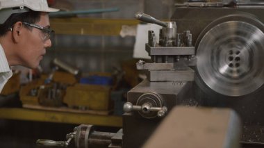 Asyalı profesyonel makine mühendisi ya da üniforma gözlüğü takan operatör güvenlik atölye metal torna fabrikası, ağır sanayi torna işçisi