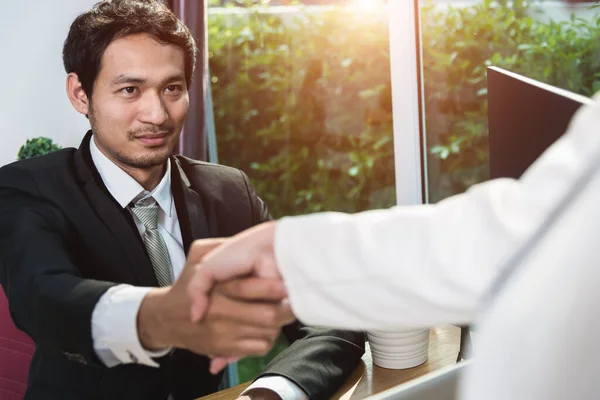 Two business man and woman greeting shaking hands during success meeting in office