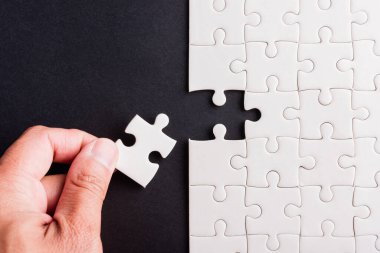 Top view düz konum son parça beyaz kağıt yapboz oyunu çözülmesi için yerleştirilen son parçalar tam bir görev, stüdyo çekimi siyah arka plan, quiz hesaplama konsepti