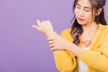 Asyalı güzel bir genç kadının portresi bilek ağrısı, karpal tünel sendromu, kadın eli ağrısı, stüdyo çekimi, mor arka plan, sağlık ve tıbbi konsept.