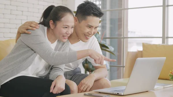 아시아인 아내가 소파에 웃으며 노트북 컴퓨터 기술로 온라인 동영상 통화를 — 스톡 사진