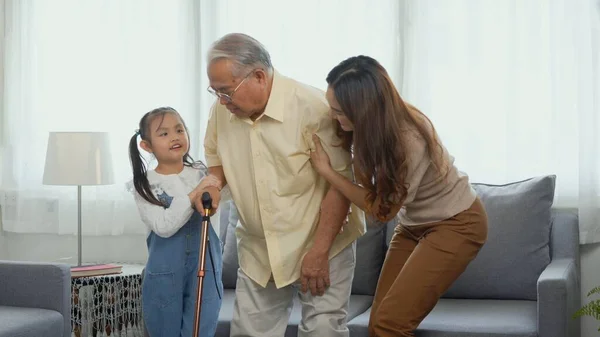 亚洲家庭 女儿和孙女照顾受膝痛折磨的外公和外公走到外面散步还有外公和外公拿着棍子 老年人的保健观念 — 图库照片