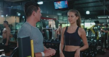Spor koçu, ağırlık kaldırma antrenmanlarını halter programıyla kadın müşteriye anlatıyor. Spor salonunda kişisel antrenör gözetiminde egzersiz yapan olgun bir adam.