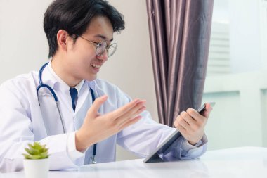 Mutlu Asyalı genç doktor yakışıklı adam gülümse gözlük tak modern dijital tablet bilgisayar kullan hastaların semptomlarını açıkla hastane ofisinde, Teknoloji Sağlık ve Tıp 'ta