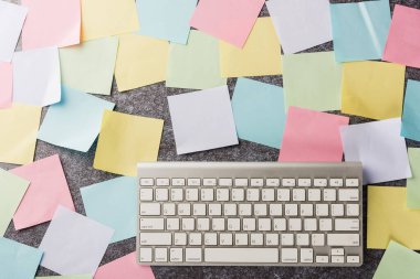 Beton zemin üzerinde modern bilgisayar klavyesi olan birçok boş kağıt yapıştırma not listesinin üzerinde, iş anımsatıcı bellek bugün konsepti