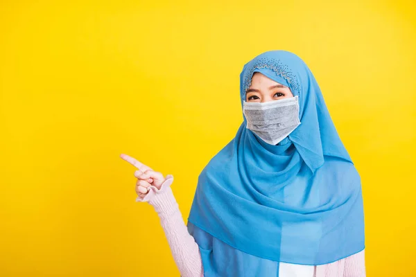 アジアのイスラム教徒のアラブ人 幸せな美しい若い女性の肖像画宗教的な服のベールヒジャーブと顔のマスク保護彼女は指の側の距離のスペースを指すコロナウイルスを防ぐために 黄色の背景に隔離 — ストック写真