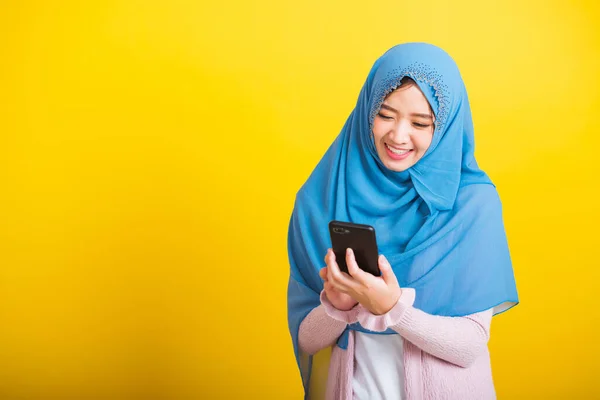 アジア系ムスリムアラブ人 幸せな美しい若い女性の肖像 イスラームという宗教的な摩耗ベールヒジャーブ面白い笑顔彼女は黄色の背景に隔離された携帯電話の読書ソーシャルメディアを使用して — ストック写真