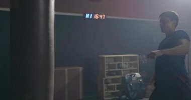 Boksör boks salonu spor salonu stüdyosunda boks eğitimi alıyor. Kickboks antrenmanlarını siyah çanta üzerinde yapıyor. Erkek eli sarıyor. Antrenman tekmesi atıyor.