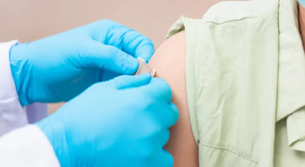 接种后 医生男子向年轻女子注射头孢病毒疫苗后肩戴橡胶防护手套 贴上胶布 Covid 19药物和保健概念 — 图库照片