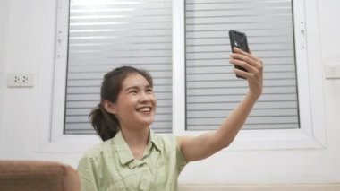 Asyalı genç bir kadın aşıyı evde engelledikten sonra aşılı sertifikasını silahlandırmak için arkadaşına akıllı telefon görüntüsü kullanıyor.