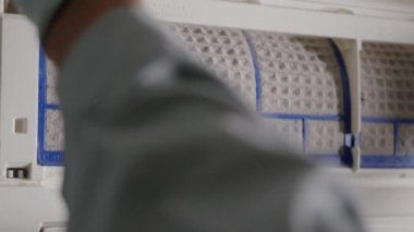 Klima filtresini kaldıran kişi, havalandırmadan temizliğe kadar havalandırma filtresini çeken teknisyenin eli.