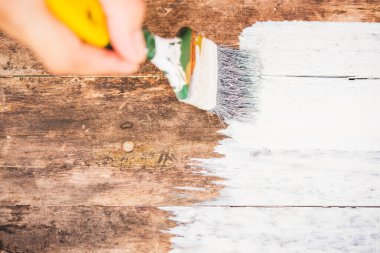 DIY, yakın plan kadın eli boya fırçası kullanıyor ya da eski ahşap rengi ahşap masa üzerine beyaz renge boyuyor