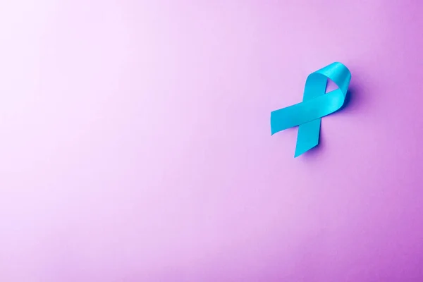 November light blue ribbon, studio shot isolated on purple background, Prostate cancer awareness month, men's health concept