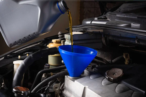 Mechanic in service to repair the car, refueling and pouring from bottle to change lubricant oil at maintenance repair service station, Energy fuel automotive concept