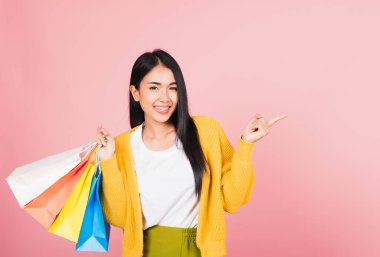 Asyalı mutlu genç kadın alışverişçinin portresi. Heyecanlı gülümsüyor. Elinde online alışveriş poşetleri var.