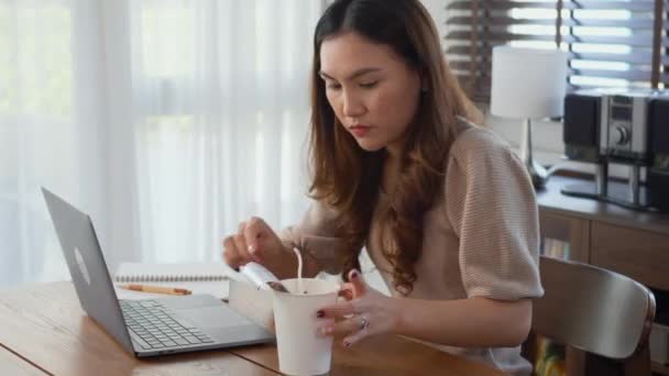 アジアのビジネス女性は自宅のノートパソコンで働いている間にインスタントラーメンを食べて 机の上に座っている幸せな美しい若い女性は 締め切りプロジェクトをやって残業 遅い時間のビジネス — ストック動画