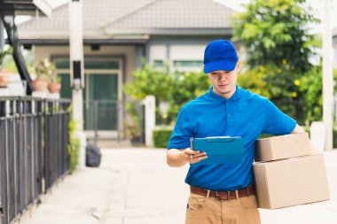 Üniformalı Asyalı genç kurye paket posta kutuları servis sevkiyatı, yürüyüş ve müşteri ev konumu, çevrimiçi alışveriş hizmeti kavramları arama