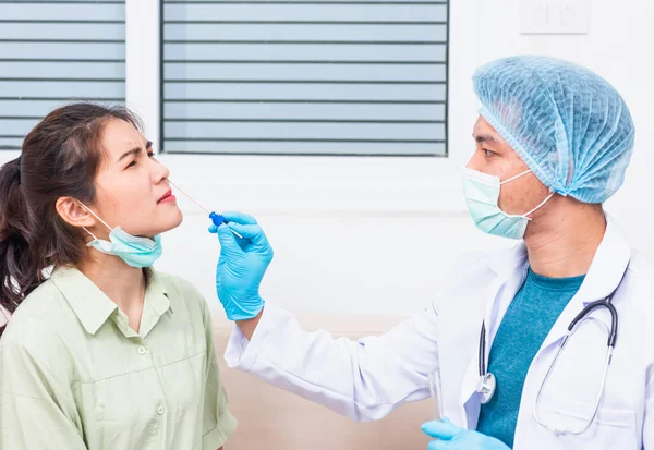 Coronavirus test, Doctor man take saliva sample through nose with cotton swab to check coronavirus test from Asian young woman, Covid-19 pandemic outbreak Medicine And Health Care Concept