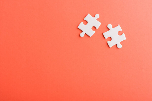 Top view flat lay of two paper plain white jigsaw puzzle game last pieces for solve, studio shot on a red background, quiz calculation concept