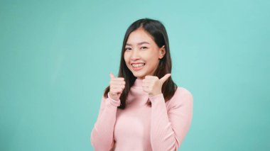 Gülümseyen genç Asyalı mutlu kadın portresi diş tellerinde silikon diş teli takıyor ve mavi arka planda parmaklarını gösteriyor. Diş sağlığı ve sağlık konsepti
