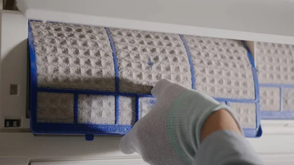 Person removing air conditioner filter, Hand of technician man working pulling dusty filter from air conditioner to cleaning in the room at home