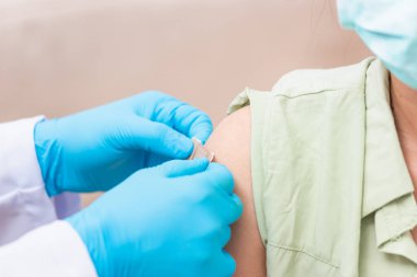 Aşı, Doktor Bey genç bir kadının omzuna koronavirüs aşısı yaptıktan sonra lastik koruyucu eldivenler yapıştırıcı bandaj sıva, Covid-19 İlaç ve Sağlık Konsepti koyuyor.
