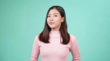 Gülümseyen genç Asyalı mutlu kadın portresi diş tellerinde silikon diş teli takıyor ve mavi arka planda parmaklarını gösteriyor. Diş sağlığı ve sağlık konsepti