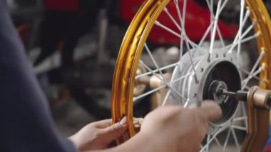 Motosiklet tekerinde çalışan teknisyenin çarkları var. Yeni çelik çarklar, motorsiklet çarkları, tekerlek hizalama aletleri.