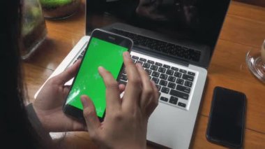 Dizüstü bilgisayarla çalışan iş kadını ve kafeteryadaki akıllı telefon yeşil ekranında bazı mesajları kontrol ediyor, iş kadını internet sitelerinde bilgi arıyor ve siyah ekranda kayıyor