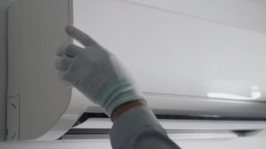 Kapıdaki havalandırmayı kontrol eden ve tamir eden teknisyen. Genç elektrikçi. Sorunları çözmek için havalandırmayı kaldırıyor.
