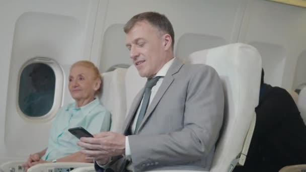 Hombre Pasajeros Senior Usando Teléfono Inteligente Avión Mientras Viaja Para — Vídeo de stock