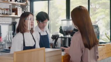 QR kod ödemesi, dijital akıllı telefon uygulaması kullanan müşteri kadın kafeteryada kahve almak için para olmadan QR kod ödemelerini tarıyor, küçük işletme dijital ödeme kabul ediyor