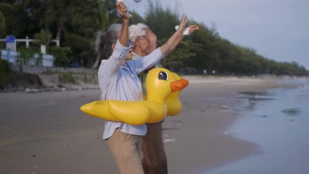 一对快乐的老夫妇戴着橡皮圈摘下医疗面罩 奔向海滩享受生活 在赢得了这场大流行病 Covid 后放松下来 为退休夫妇计划人寿保险 — 图库视频影像