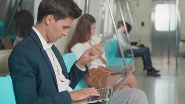 通勤中の午前中に地下鉄で働くノートパソコンを使って座っている若い白人のビジネスマン 人々の交通概念 — ストック動画