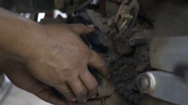 Tamirci, motor tamircisinin manyetik tekerlek kılıfını kaldırıyor. Dükkandaki motosiklet, otomatik motor tamiri.