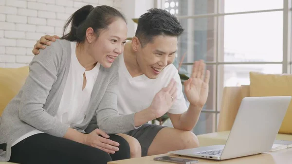 아시아인 아내가 소파에 웃으며 노트북 컴퓨터 기술로 온라인 동영상 통화를 — 스톡 사진