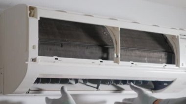 Kapıdaki havalandırmayı kontrol eden ve tamir eden teknisyen. Genç elektrikçi. Sorunları çözmek için havalandırmayı kaldırıyor.