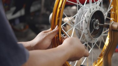 Motosiklet tekerinde çalışan teknisyenin çarkları var. Yeni çelik çarklar, motorsiklet çarkları, tekerlek hizalama aletleri.