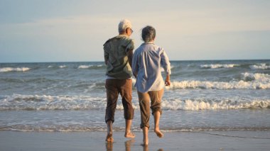 Mutlu Asyalı üst düzey erkek ve kadın çiftler kumsala koşar ve eğlenceli, romantik yaşlılar yaz tatilinin tadını çıkarırlar. Emekliler konseptinde hayat sigortası planlarlar.