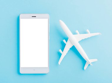 Dünya Turizm Günü, Minimum oyuncak model uçak, uçak ve akıllı telefon boş ekran dairesi, mavi arka planda izole edilmiş stüdyo çekimi, aksesuar uçuş tatili konsepti