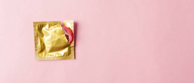 Dünya seks sağlığı ya da AIDS Günü, Top view düz kondom paketi yırtık, stüdyo çekimi pembe arka plan, güvenli seks ve üreme sağlığı konsepti.