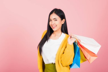 Asyalı mutlu genç bir kadının portresi. Gülümseyen genç bir alışverişçi. Elinde online alışveriş poşetleri tutarken heyecanlanıyor.