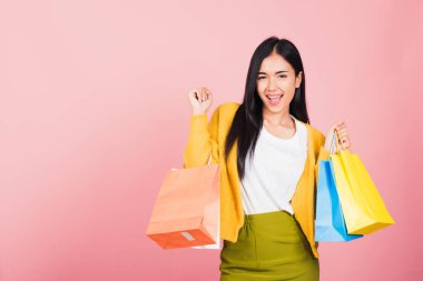 Asyalı mutlu genç bir kadının portresi. Gülümseyen genç bir alışverişçi. Elinde online alışveriş poşetleri tutarken heyecanlanıyor.