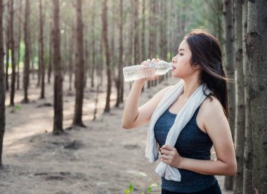 Doğa Park Ormanı 'nda spor sonrası su şişesi içen güzel genç bir kadın.